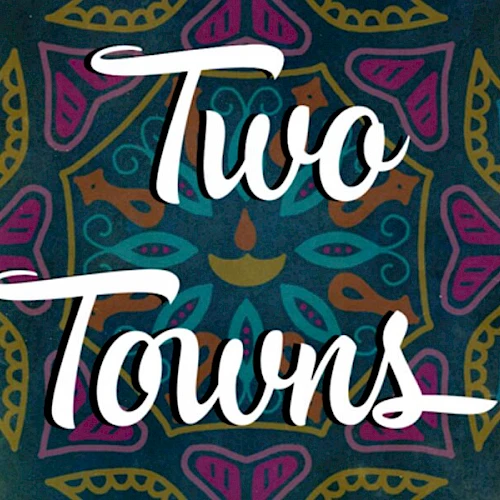 The image features the text "Two Towns" over a colorful, intricate mandala design.